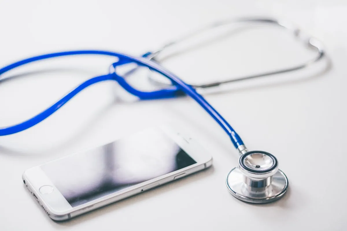 A smartphone and blue stethoscope on a clean white surface, emphasizing modern healthcare.
